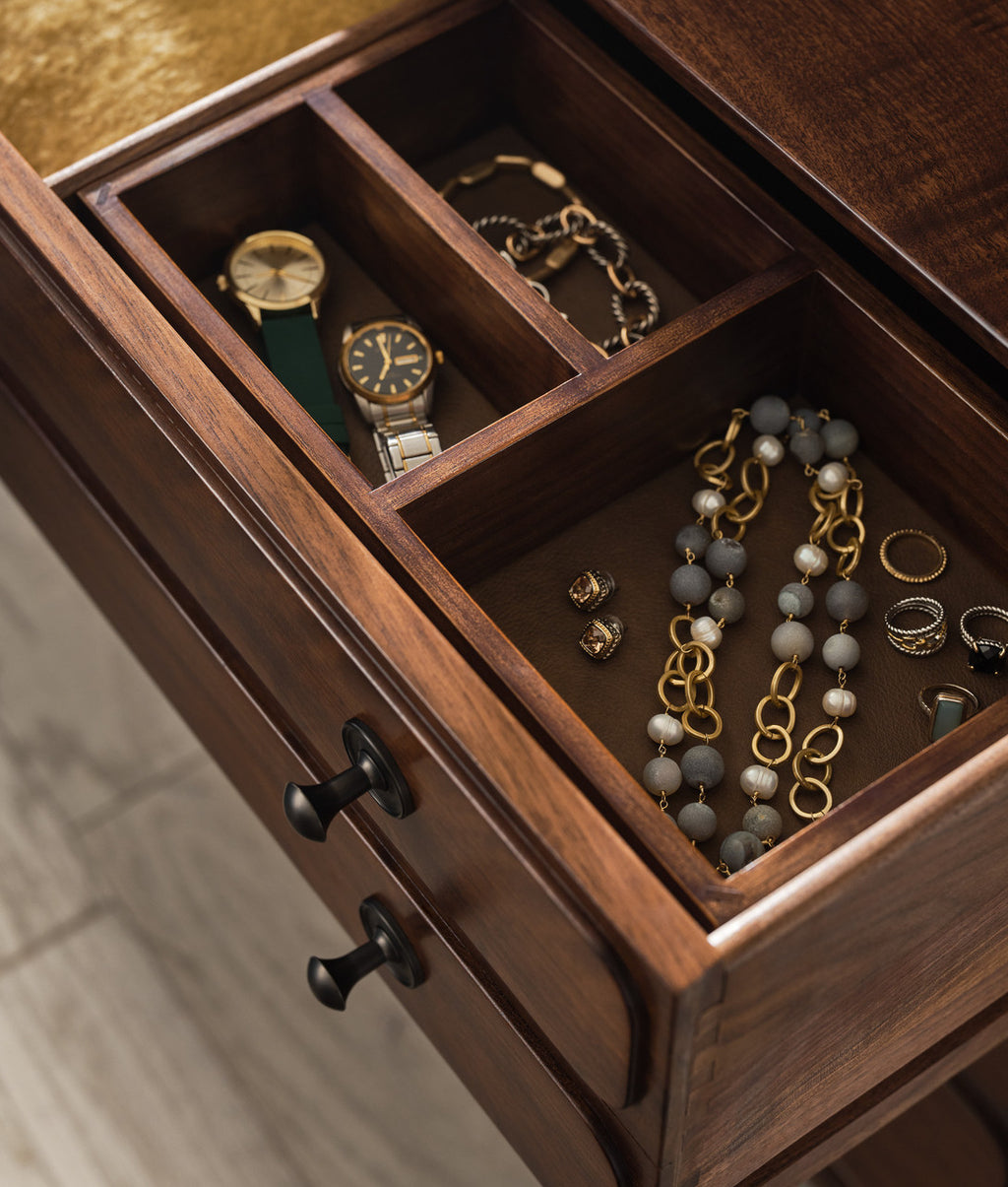Wooden jewelry drawer with watches, necklaces, and rings