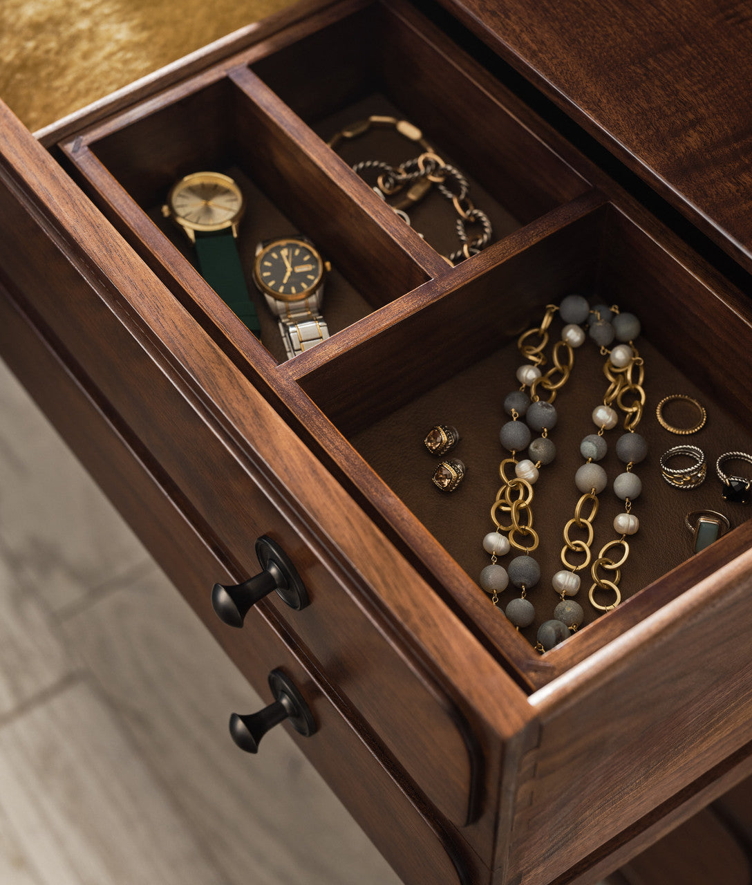 Wooden jewelry drawer with watches, necklaces, and rings