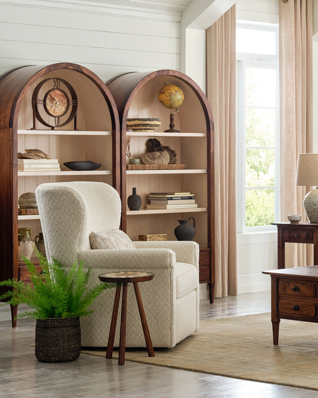 Cozy living room with a beige armchair, bookshelves, and decorative items.