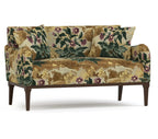 A small upholstered loveseat with rolled arms, dark wood legs, and a dense floral tapestry-style pattern in beige, olive green, and purple on a white studio background.