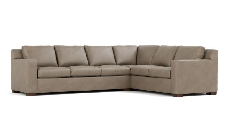 A modern sectional sofa in a taupe beige fabric, featuring a right-facing L-shape configuration with plush back cushions and seat cushions, supported by dark wood legs, shown against a plain white background.