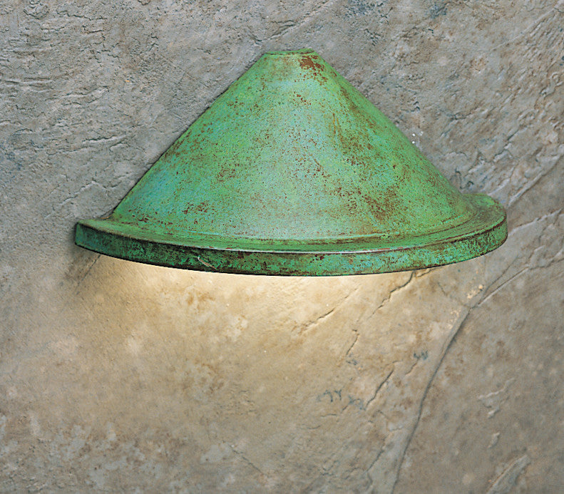 Green metal wall light fixture on a textured stone wall