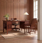 A warm brown wooden writing desk with matching armchairs in a classic office setting with wood-paneled walls, a window, and a rug.