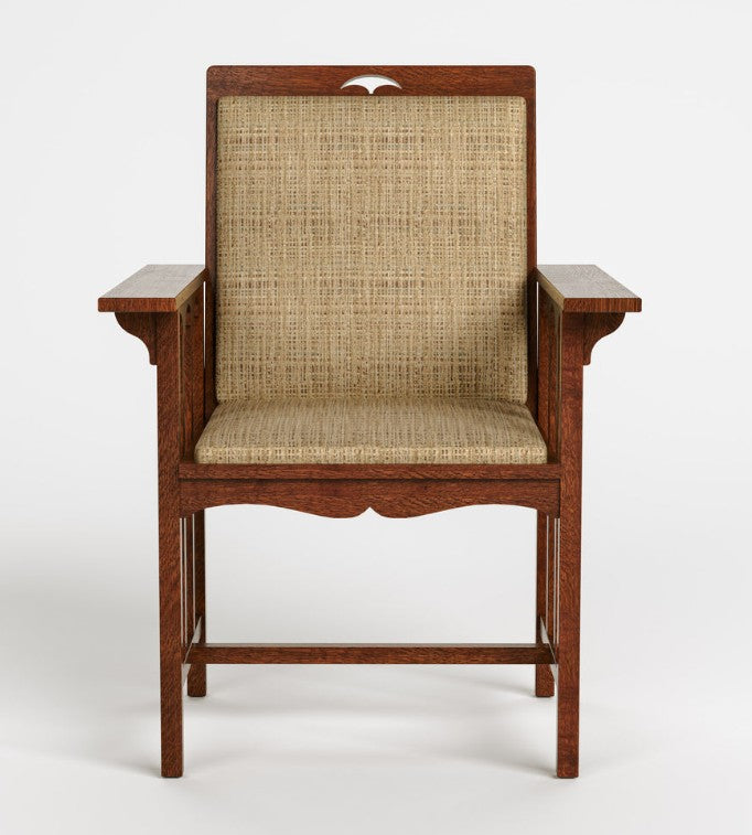 A wooden armchair with a woven cane backrest and seat, featuring a reddish-brown wood frame and armrests, shown against a plain light gray background.