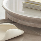 Round wooden table with a white ceramic dish and books on a light background