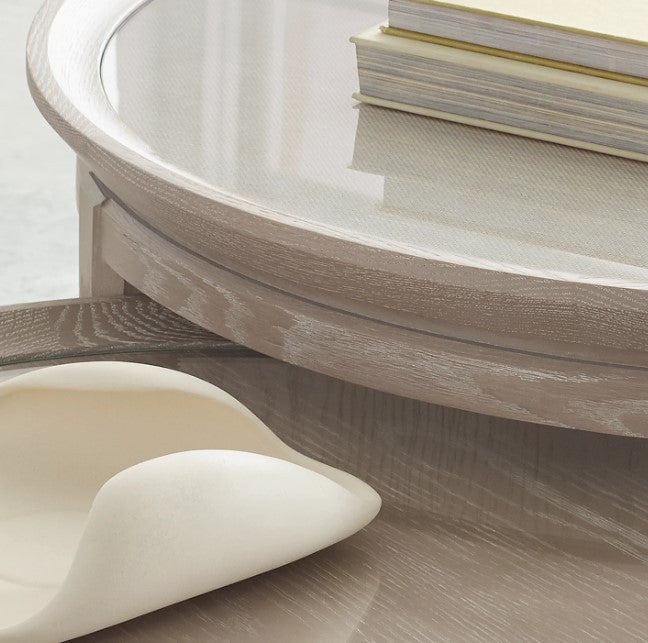 Round wooden table with a white ceramic dish and books on a light background