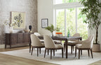 Dining room with wooden table and chairs near large windows with a view of greenery.