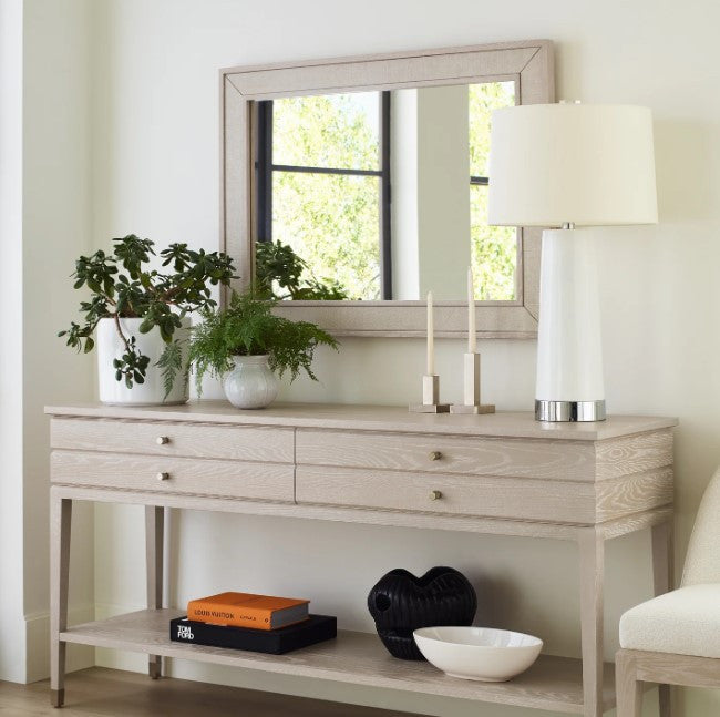 Light wood console table with decorative items against a white wall