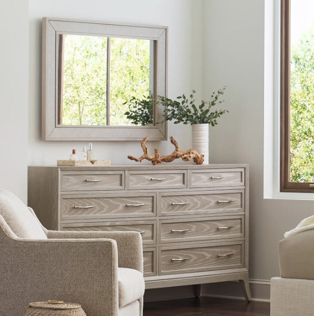 Wooden dresser with mirror in a room with a window and plant