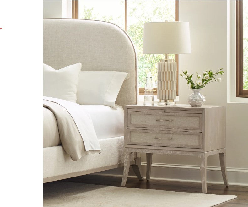 Neatly arranged bedroom with a bed and nightstand featuring a lamp and vase.