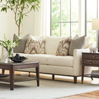 Beige sofa with patterned pillows in a living room setting with a coffee table and decorative items.