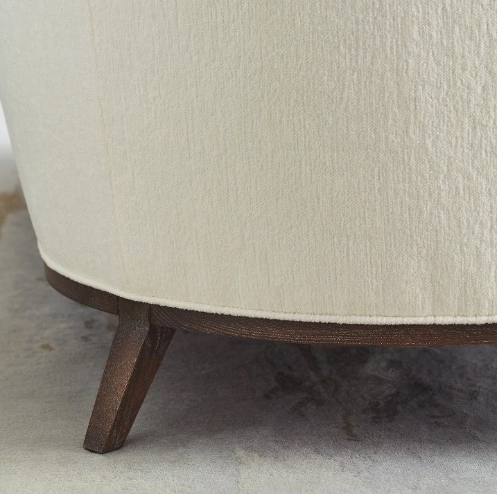 Close-up of a beige upholstered chair with wooden legs on a carpeted floor.