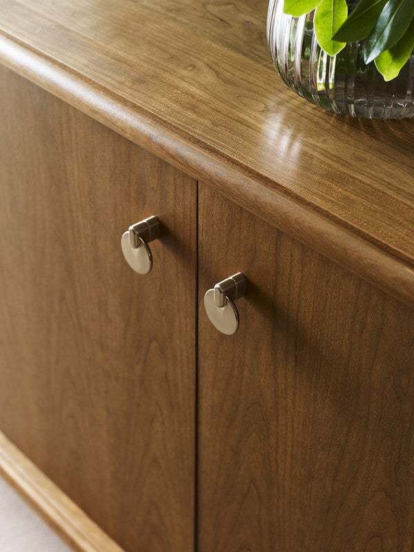 Wooden cabinet with round metallic handles and a plant on top