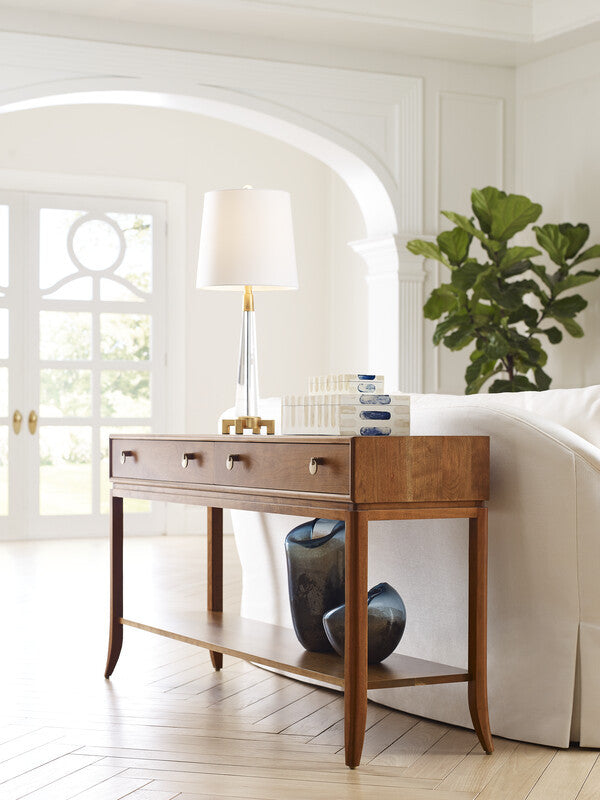 Wooden console table with decorative items in a room with white walls and a plant.