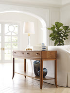 Wooden console table with decorative items in a room with white walls and a plant.