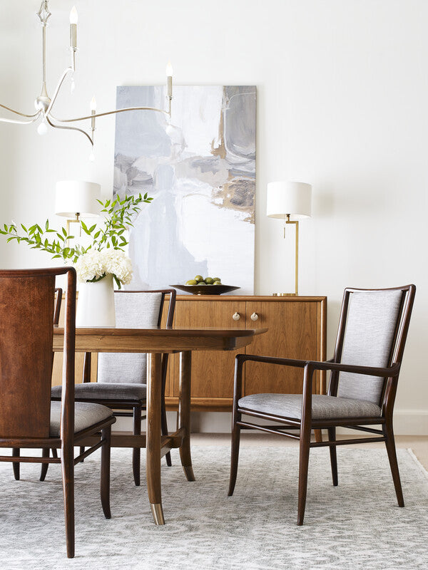 Dining room with wooden table and chairs, abstract painting, and lamp.