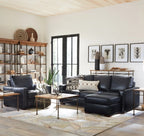 Modern living room with black leather sectional sofa, coffee table, and decorative items.