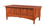 A wooden desk with a warm reddish-brown finish, featuring a paneled front and a slanted desktop, shown against a plain white background.
