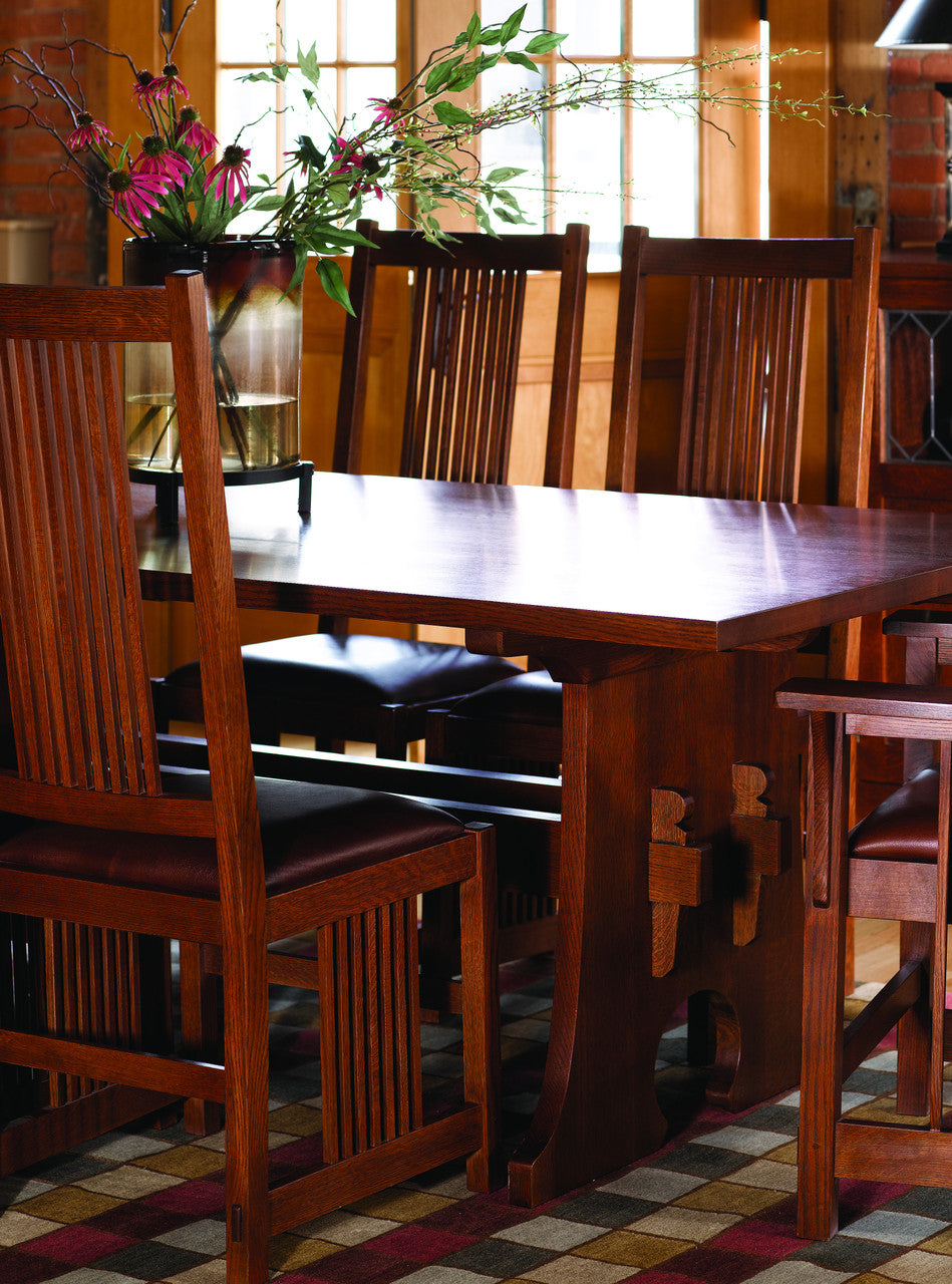 Wooden dining table with chairs in a room with large windows.