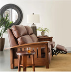 A brown leather recliner chair with a matching footrest and wooden side table, styled in a modern living room setting with a side table, lamp, and plants.
