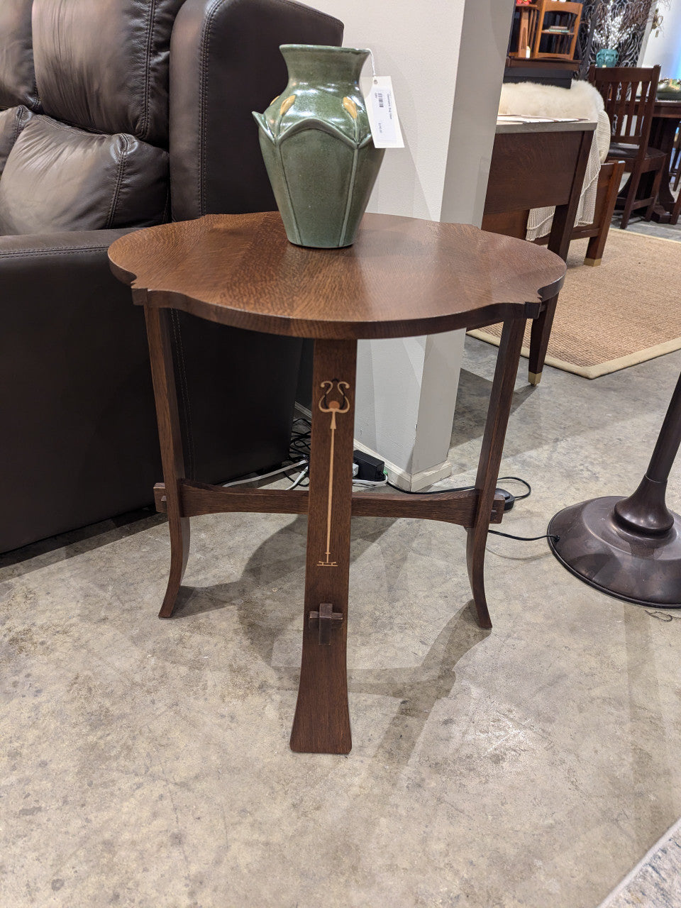 Stickley tea table with a green vase on top in a showroom setting