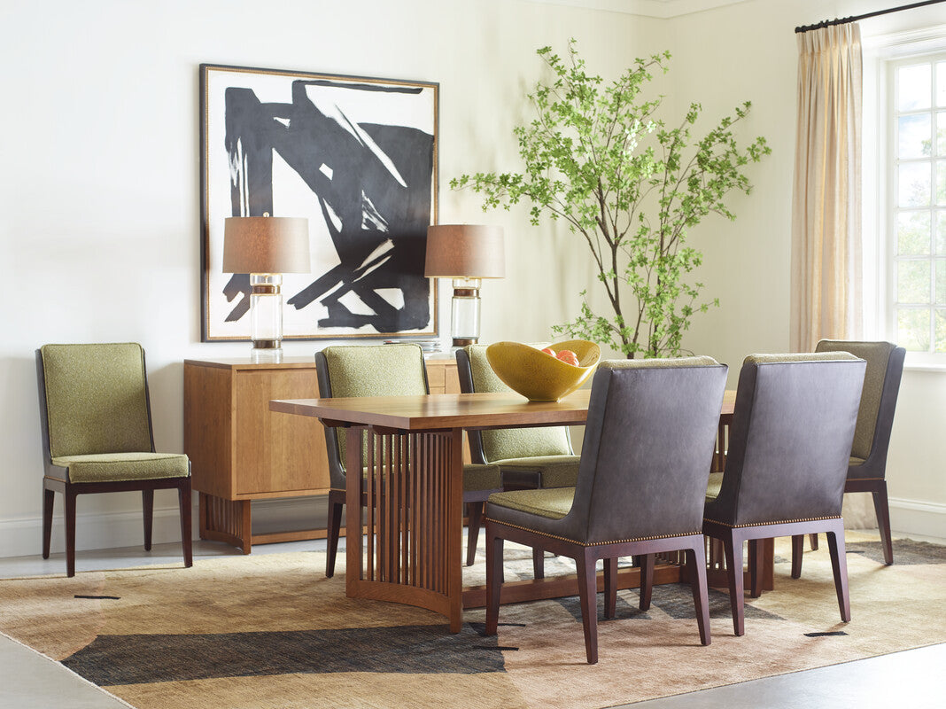 Dining room with wooden table and chairs, abstract art on the wall, and a plant.