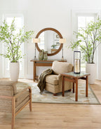 Living room with beige sofa, wooden coffee table, and decorative plants. The park slope mirror looms over the table. 
