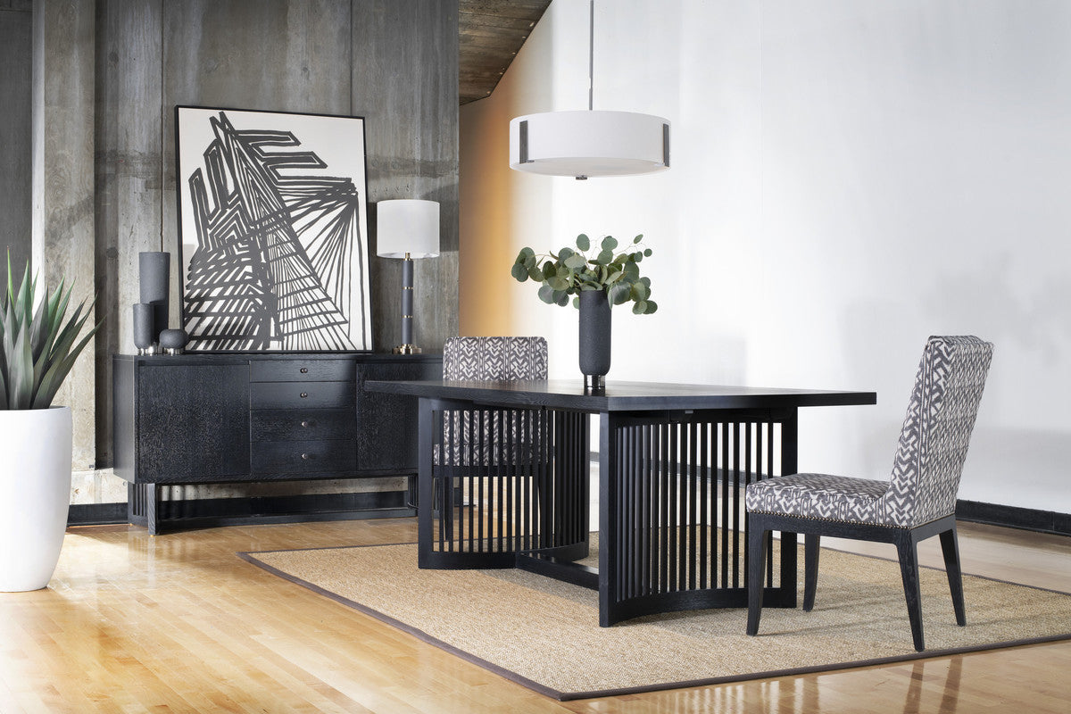 Modern dining room with black table and chairs, abstract art, and decorative elements.
