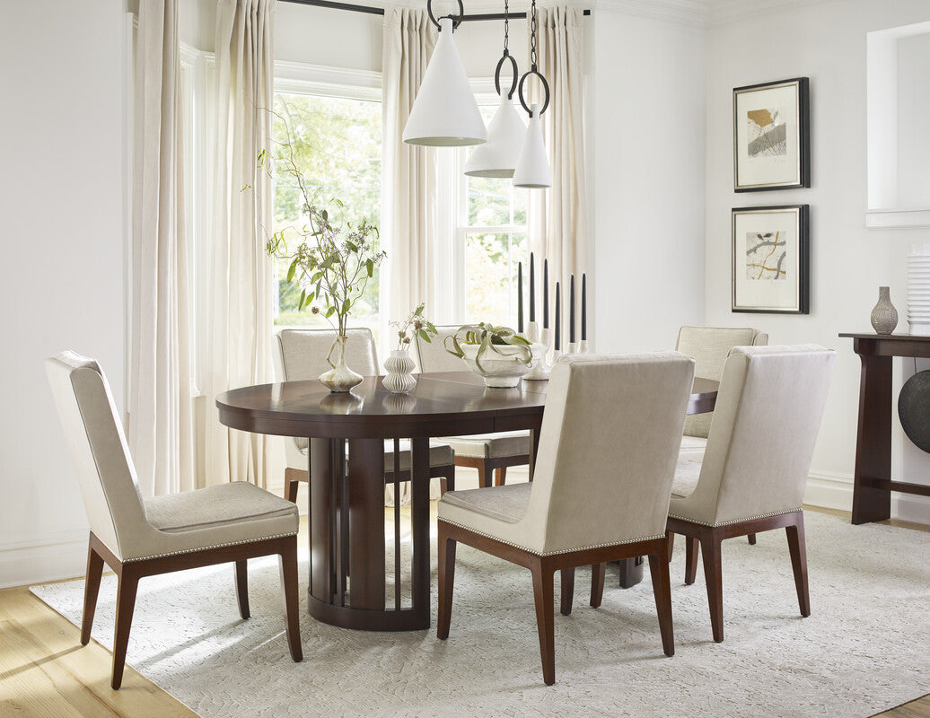 Dining room with a round wooden table and four chairs with white cushions.