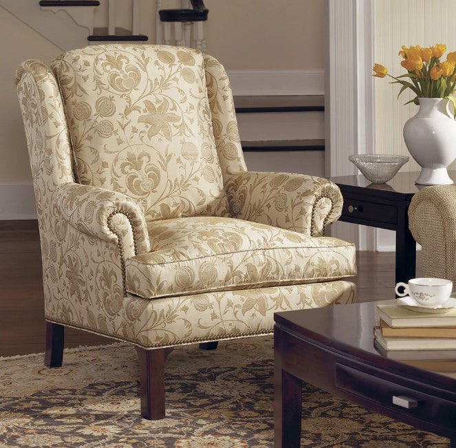 Patterned armchair in a living room setting with a coffee table and flowers.