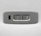 A rectangular brushed metal control panel with two toggle switches and a small vertical port, shown against a textured white background.