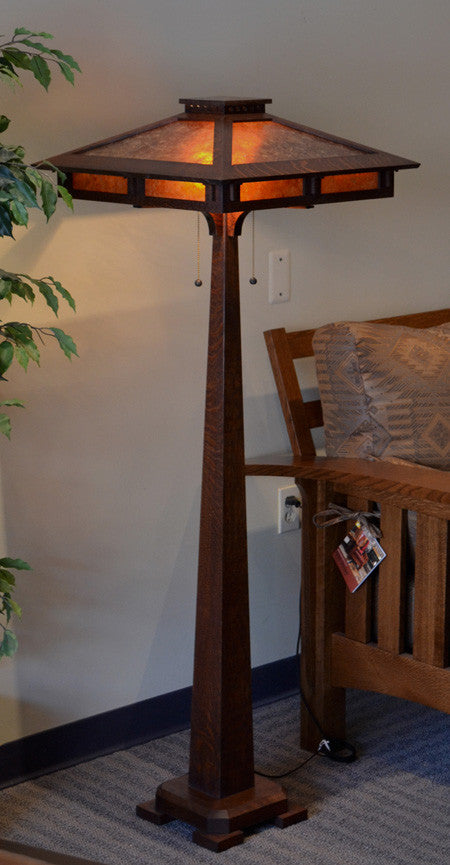 Wooden floor lamp with a decorative shade in a room setting.