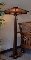 Wooden floor lamp with a decorative shade in a room setting.