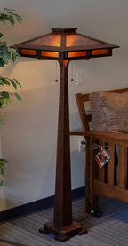 Wooden floor lamp with a decorative shade in a room setting.