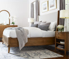 Neatly made bed in a bedroom with wooden furniture and decor.