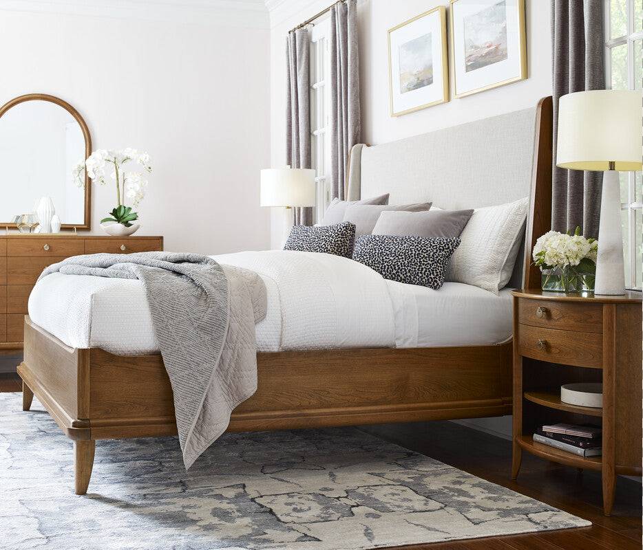 Neatly made bed in a bedroom with wooden furniture and decor.