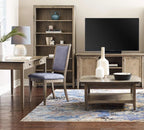 A styled living room scene featuring a rustic wood media console with a black television, a matching coffee table, a blue upholstered chair, and a wooden bookshelf in a warm neutral interior.