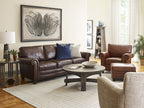Living room with brown leather sofa, armchair, and round coffee table. Roycroft magazine pedestal is also included. 