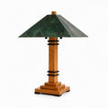 A table lamp with a dark green textured glass or stone conical shade, a warm medium-brown wooden column and tiered base, and black metal accents, shown on a plain white background.