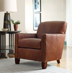 Brown leather armchair in a living room setting with a lamp and plant.