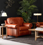 Brown leather sofa in a living room setting with lamps and a plant.