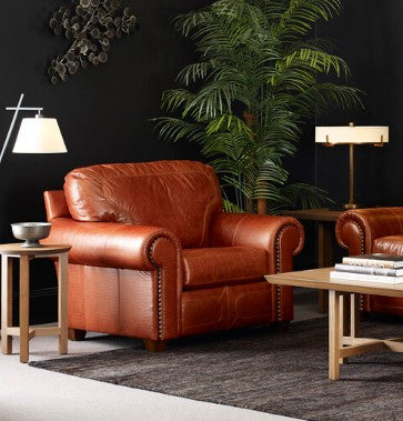 Brown leather sofa in a living room setting with lamps and a plant.
