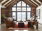 Cozy living room with brown leather furniture and large windows overlooking a scenic view.