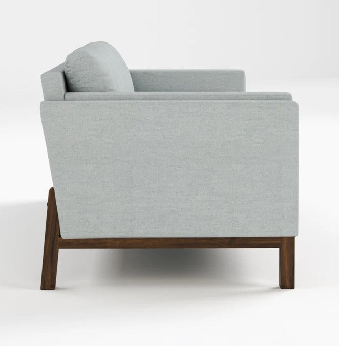 A modern light gray upholstered armchair with a dark brown wooden frame, shown from a side angle against a plain white studio background.