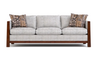 A three-seat sofa with light gray textured fabric upholstery and a medium brown wooden frame, styled with two patterned throw pillows on a white background.
