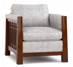 A classic armchair with a textured light gray fabric upholstery and a dark brown wooden frame featuring a decorative slatted side panel.