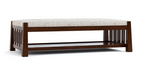A ottoman and cocktail table with a dark brown frame, featuring a light beige textured upholstered seat cushion and a lower open shelf, shown against a plain white background.