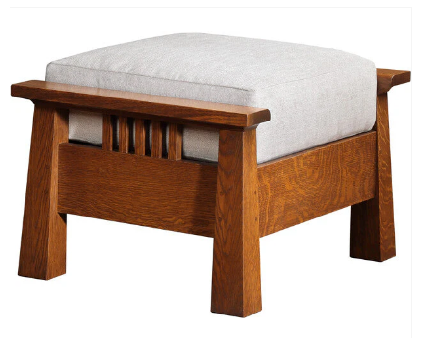 A wooden ottoman stool with a thick, square, light gray upholstered cushion on a medium brown wood frame, shown against a plain white background.