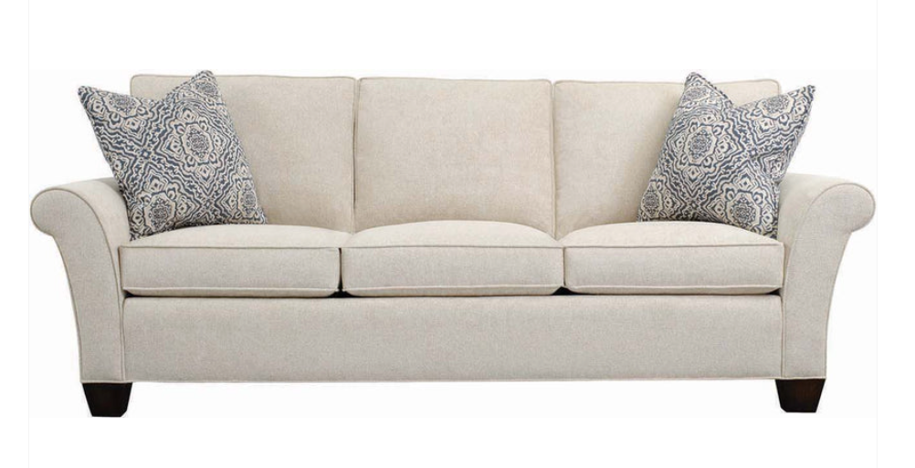 A three-seater upholstered loveseat in a light beige fabric, featuring two decorative throw pillows with a gray and white paisley pattern, set against a plain white background.