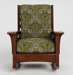 A wooden rocking chair with a dark brown wood frame and green damask patterned upholstery, shown against a light gray background.